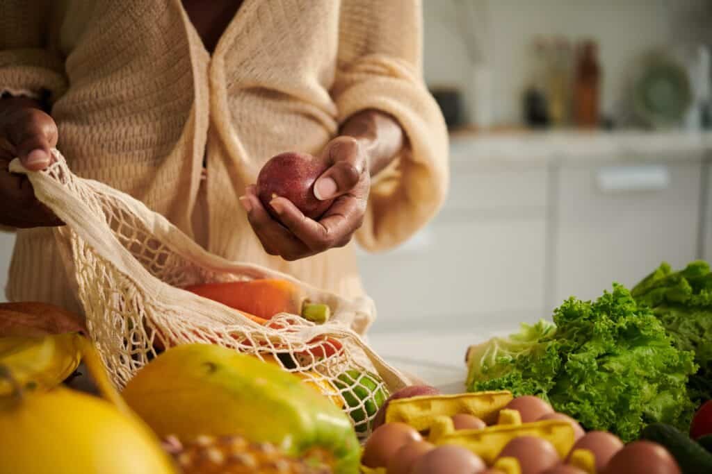 Woman unpacks fresh ingredients from reusable net bag in bright kitchen
