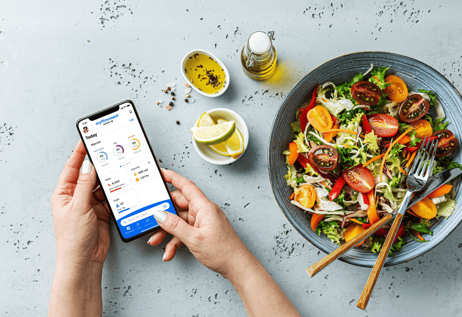 MyFitnessPal app on the phone next to colorful salad with tomatoes and greens